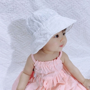 Klein Aziatisch meisje zittend met roze jurk en witte baret kijkend naar rechts