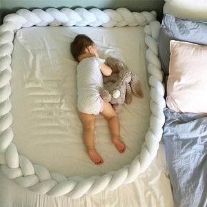 Beschermende stootrand voor een meisjesbed op een bed met een baby erin in een huis