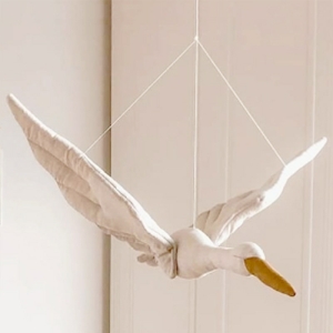 Pop in de vorm van een witte zwaan met een beige snavel hangend aan drie touwtjes voor een witte muur