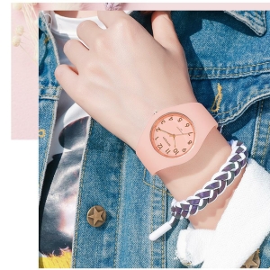 Een jong meisje met alleen haar bovenlichaam zichtbaar, ze draagt een spijkerjasje en een effen roze siliconen horloge met armband