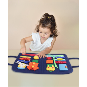 Klein meisje op een tafel dat de ritssluiting op het leerbord probeert te openen met verschillende voorwerpen zoals een knoop, een drukknoop, een koord, een clip, een riem, enz