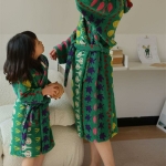 Jong brunette meisje met een volwassene in een kamer, beiden dragen groene plantaardige badjassen