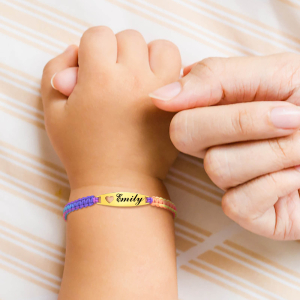 Babyhand met een gekleurde armband om de pols en de hand van een volwassen vrouw