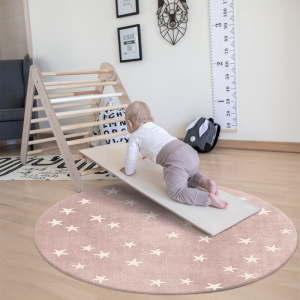 Baby speelt op een rond tapijt in een slaapkamer