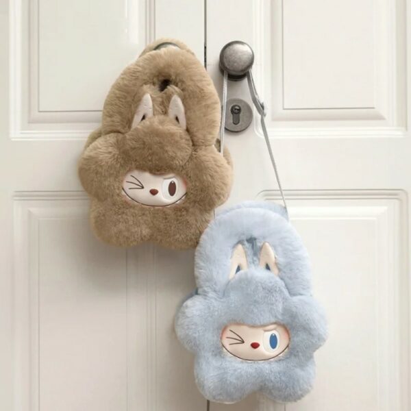 twee kleine zachte handtasjes in bloemvorm met knipogend Labubu-gezicht en grote konijnenoren, één lichtblauw en één lichtbruin, hangend aan een deurklink