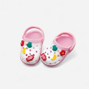 Mini klompjes in Crocs-stijl, roze en wit, met kleurrijke charms bovenop, op neutrale achtergrond.